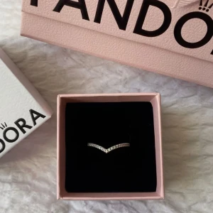 Ring från Pandora - Elegant ring från Pandora i en stilren design. Ringen har en V-formad stil med glittrande stenar som ger en lyxig känsla. Asken ingår , ringen är i storlek 46