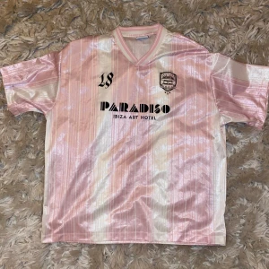 Fotbollströja Bershka - Säljer en snygg rosa och vit randig fotbollströja från Bershka i samarbete med Paradiso Ibiza Art Hotel. Oversized passform, köpt för 800kr.