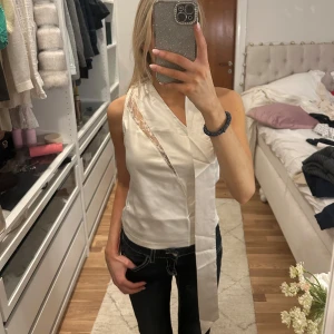 Vit omlottopp - Snygg vit omlottopp från Cider med spetsdetaljer. Toppen är ärmlös och har en elegant knytning vid halsen. Perfekt för en stilren look. Aldrig använd med lapp kvar!! Så otroligt fin men tyckte inte den passade som jag ville därav säljer jag den.