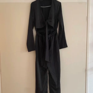 Jumsuit i satin  - Jättesnygg jumpsuit med knytning fram och vida ben. Endast använd vid få tillfällen!