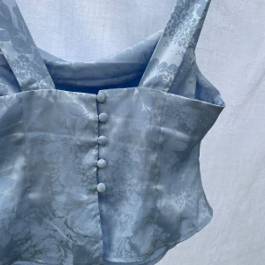 Blå topp - Fin blå topp i glansigt material, från asos, storlek 36 men liten i storleken. Nyskick, då den var för liten för mig.