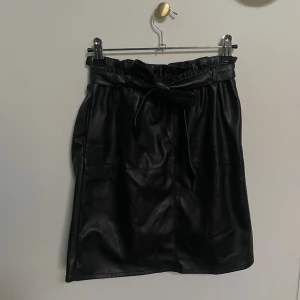 Only Kjol - En svart kjol i läderimitation från Only. Med skärp i midjan.