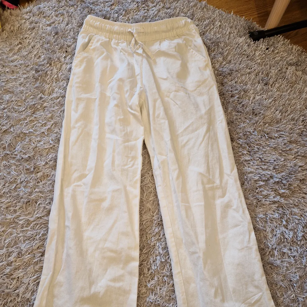 Säljer ett par bekväma och stilrena vita linnebyxor från 157. De har en elastisk midja med snörning. Perfekta för en avslappnad sommarlook! Bra skick.. Jeans & Byxor.