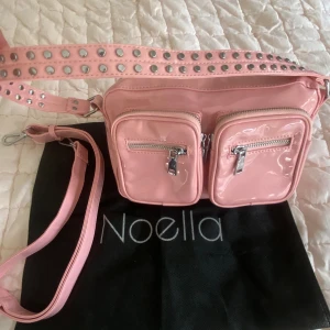 Noella väska - Supersöt rosa lackerad noella väska, kommer med ett extra band och en påse👛. Finns en väldigt liten missfärgning i ett hörn (se sista bild), men syns väldigt lite.