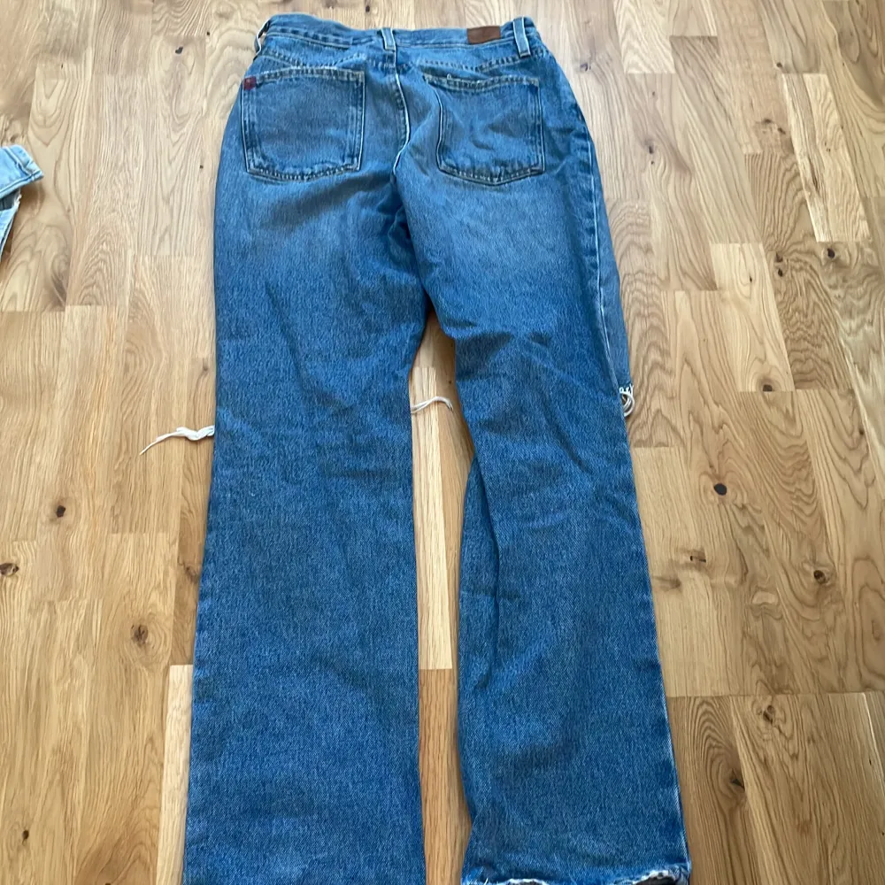 Säljer ett par snygga blå bootcut jeans från BDG. De har en cool slitning på framsidan som ger en avslappnad och trendig look. Perfekta för en casual outfit! Tillverkade i Mexiko.. Jeans & Byxor.