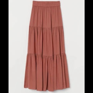 Brun långkjol i viskos - Säljer en superfin ”mörk orange-brun” långkjol i viskos. Kjolen har en elastisk midja och flera lager som ger en härlig volym. Perfekt för både vardag och fest! 🧡Köpt för 299kr, säljer för endast 120kr.