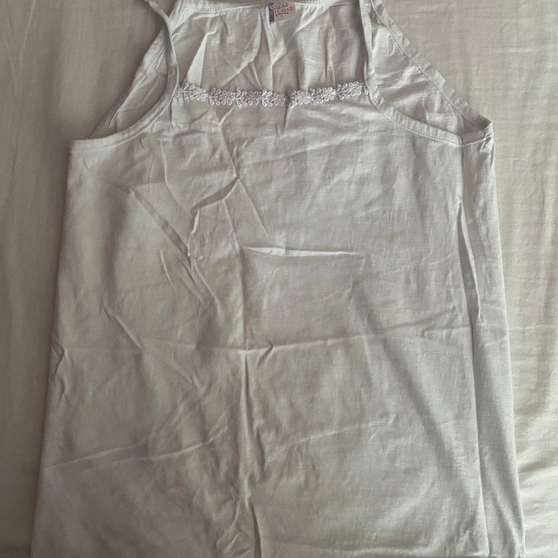 Vit ärmlös linnetopp med spetsdetalj