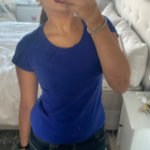 Blå t-shirt från JC - Säljer en snygg blå t-shirt från JC i storlek XS. Den är kortärmad och har en rund halsringning. Perfekt för vardagsbruk eller att styla upp med accessoarer för en mer festlig look.