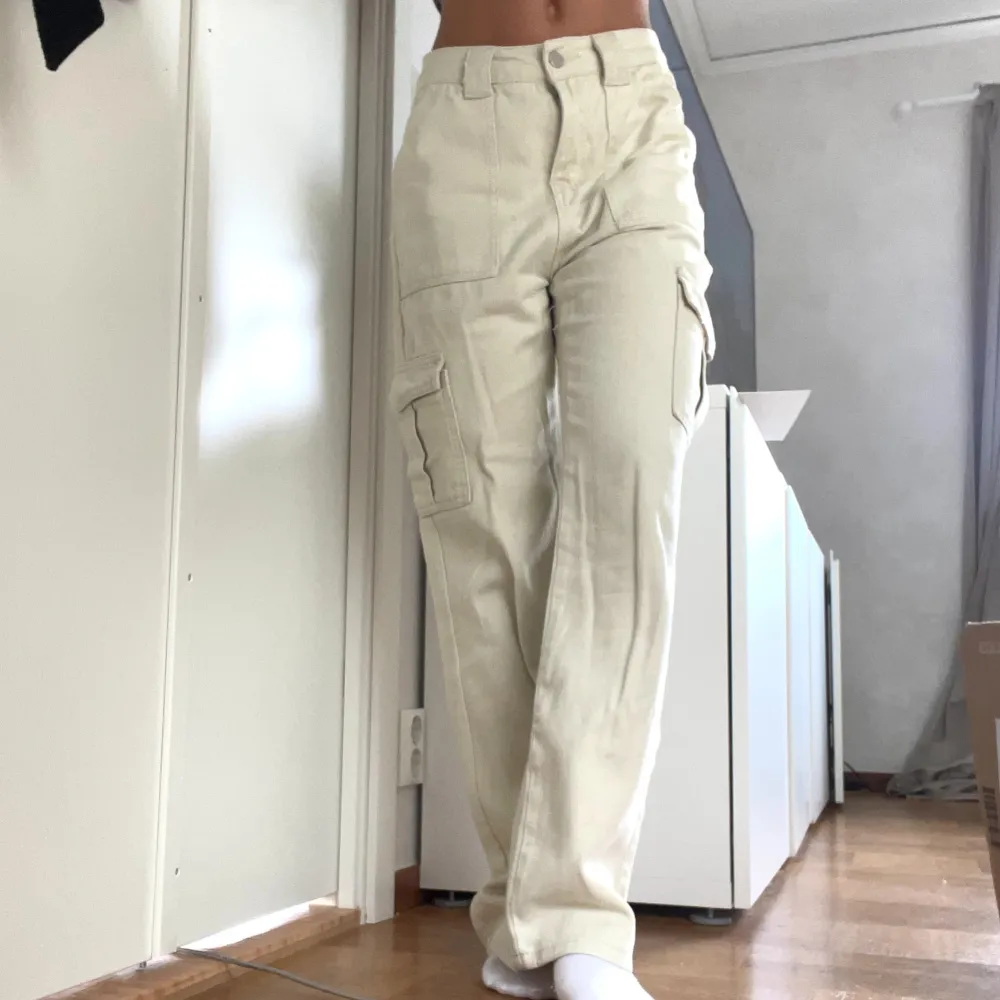 Säljer ett par snygga beige cargobyxor med hög midja. De har flera praktiska fickor på sidorna och en loose passform som ger en avslappnad stil. Perfekta för både vardag och äventyr!. Farkut & Housut.