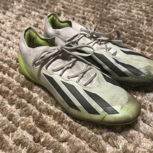 Fotbollsskor från Adidas - Använda några gånger som man kan se men tvättas lätt bort. Elite modell adidas crazy fast. Säljer ett par Adidas fotbollsskor i vitt och neongrönt med svarta detaljer. Skorna har snörning och är designade för optimal prestanda på planen. Perfekta för fotbollsspelare som vill ha stil och funktion.