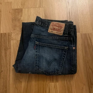 Mörkblå jeans från Levi's 559 - Säljer ett par klassiska mörkblå jeans från Levi's. De har en rak passform och är tillverkade i slitstarkt denim. Perfekta för en avslappnad stil. Levi's-loggan syns tydligt på bakfickan.                      Storlek:                                                                               W:34 L:34