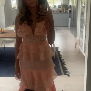 Lång rosa balklänning med volanger - Säljer denna jättefina balklänning med volang från True decendence i färgen peach. Använd bara en gång! Jag är 171 och den går ner till marken på mig, hade dock inga klackar på bilderna- så den funkar även om man är lite kortare med klackar!☺️Kanten har även blivit lite uppvikt längst ner (då den var lite lång) och har små defekter där den blivit lite missfärgad om man kollar noga, men inget av detta skulle jag säga syns då det är en volang där!- se sista bilden! Ny pris 2,100!+ frakt💕