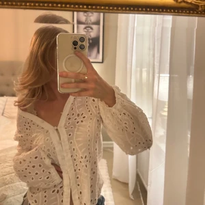 En mönstrad vit blus med hål - En fin blus mönstrad med hål och knappar, perfekt för vår och sommardagar, ballongärmar