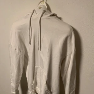 Vit hoodie med ficka från Only & Sons - Säljer en stilren vit hoodie med känguruficka och justerbar huva. Perfekt för en avslappnad look. Passar bra till jeans eller mjukisbyxor. Hör av dig vid intresse! Storlek XS.