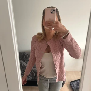 Rosa stickad kofta från Heart of Lovikka - Säljer en söt rosa stickad kofta från Heart of Lovikka. Koftan har ett diskret mönster och knappar framtill. Perfekt för en mysig dag eller en sval kväll. 💖Bra skick men vissa trådar som sticker ut.