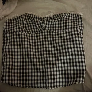 Svartvit rutig tubtopp - Säljer en söt svartvit rutig tubtopp med spetsdetaljer längs överkanten.  Använd fåtal gånger🩷