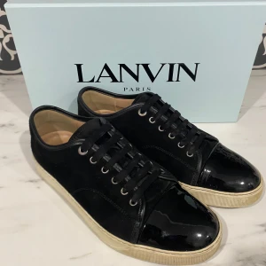 Svarta Lanvin sneakers UK 8 - Stilrena lanvins som är i 8/10 skick. Köpta förra året och kommer i storlek UK 8 vilket motsvarar storlek 41-42 EU. Skorna kommer med den originala boxen, två dustbags, och extra skosnören. 