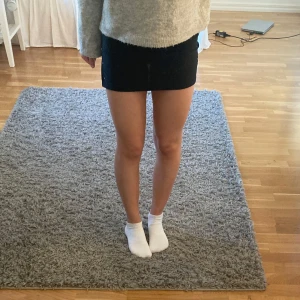 Svart kortkjol med glitter stenar längs sidan - Snygg svart kortkjol med glitter stenar längs sidan. Perfekt för en uppklädd look. Kjolen har en tight passform som framhäver figuren. Passar mig som har XS