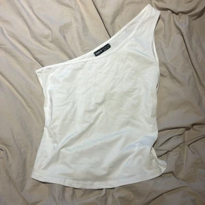 Vit osymettisk topp - Säljer min vita topp från SHEIN i stl L, aldrig använd!