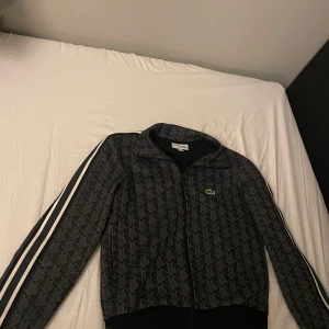 Lacoste zip  - Säljer nu min riktigt feta Lacoste zip. Unikt monogram och passar till det mesta. Storlek xs. Knappast använd då den blev för liten. Det är bara att höra av sig vid fundering!