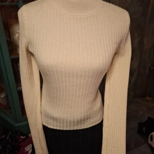 Beige ribbad tröja från divided - Säljer en stilren beige ribbad tröja från divided. Tröjan har en tight passform och långa ärmar, perfekt för kyligare dagar. Den är gjord i ett mjukt material som känns skönt mot huden. Passar utmärkt till både jeans och kjol. Den är lite nopprig om armarna. Syns på bilderna.