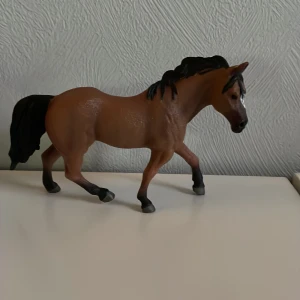 Leksaks häst - Detaljerad brun hästfigur med svart man och svans. Figuren har en realistisk design och är perfekt för samlare eller som leksak. Tillverkad i plast med en slät yta och noggrant utformade detaljer.