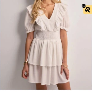 Vit klänning med volangdetaljer - Säljer en söt vit klänning med volangdetaljer och v-ringning. Har endast använt den en gång så i nyskick. Nypris 399kr. Skriv för privata bilder!