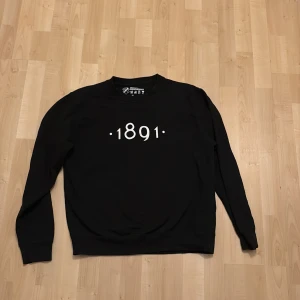 Svart sweatshirt från AIK - Säljer en svart sweatshirt från AIK med trycket '1891' på framsidan. Tröjan är i officiellt merchandise och har långa ärmar. Perfekt för AIK-fans som vill visa sitt stöd året runt.