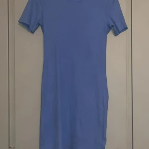 Blå klänning - Snygg blå klänning från Stories i storlek S (36-38). Den har en enkel och stilren design med korta ärmar och en normal passform. Perfekt för en avslappnad look.