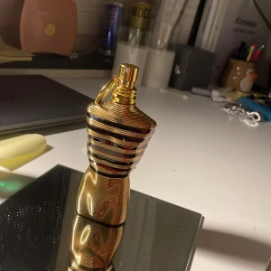 jean paul gaultier la male elixir - Säljer en cool parfymflaska i form av en manlig torso med guld- och svart randigt mönster. Perfekt för den  som vill ha något annorlunda och stilrent. 30ml kvar!
