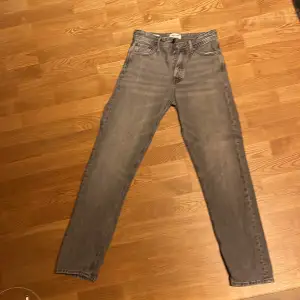 Säljer ett par grå jeans från Jack & Jones i modellen Relaxed/Chris. De har en avslappnad passform och är perfekta för en casual look. Jeansen är i bra skick och har en klassisk femficksdesign. Perfekta för både vardag och fest! Nypris ca 7-800kr