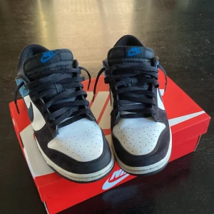 Nike dunk low - Jag säljer mina Nike dunk low  i storlek 42,5 för att de är för små. De är i väldigt bra skick bara lite slitna i hälen som du  ser på sista bilden och lite smutsig sula och lite creasade. Det är både mocha och läder på skorna. Frågor? Skriv till mig