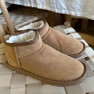 Helt nya Vinter mini boots - Nya uggs liknande fodrade mini boots, bruna med vit päls inuti. Säljer pga fel storlek. Endast provade en gång hemma. Varma och jätte sköna perfekt till vintern❄️