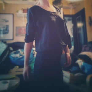 Svart topp med spetsdetalj - Säljer en stilren svart topp med spetsdetalj vid halsringningen. Den har en lös passform och trekvartsärmar, perfekt för både vardag och fest. Toppen är i bra skick och passar till många olika outfits. Perfekt för höst och vår!