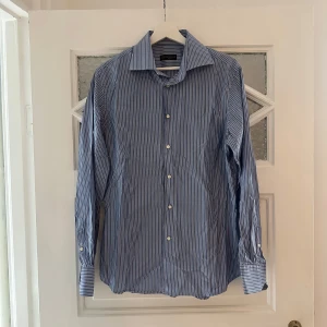 Corneliani skjorta (herr) - Herrskjorta från Corneliani. Storlek 40 men insydd i midjan för att bli slim fit.