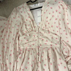 Långklänning - Säljer denna fina klänning från BYIC då den inte blivit använd tyvärr..  det saknas en knapp men man får med 2 extra knappar så det är enkelt att sy på  Nypris:900kr