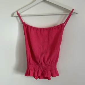 Rosa linnetopp från Gina Tricot - Säljer en superfin rosa linnetopp från Gina Tricot. Den är ärmlös med smala axelband och har en söt volangdetalj längst ner. Perfekt för sommardagar eller en festlig kväll. Toppen är i ett skönt och lätt material.