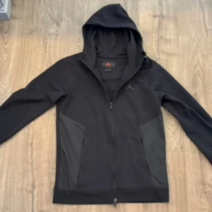 Svart hoodie från Jordan - Säljer en snygg svart hoodie från Jordan. Den har en dragkedja framtill och en justerbar huva. Perfekt för både träning och vardagsbruk. Den är i bra skick och redo för en ny ägare!