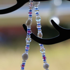 Färgglatt pärlhalsband - Säljer ett superfint halsband med färgglada pärlor i olika nyanser av blått, vitt och lila. Perfekt för att liva upp vilken outfit som helst! Halsbandet har en enkel och lekfull design som passar både till vardags och fest.