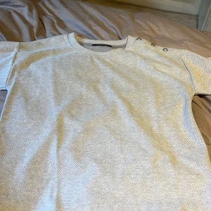  Ralph Lauren tröja  -  Jättebra skick grå mönstrad kortärmad tjocktröja med tre knappar / nitar i silver på vänster axel 