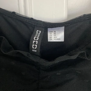 Svart klänning från H&M - Säljer en superfin svart klänning från H&M i storlek XS. Den har puffiga, genomskinliga ärmar med prickigt mönster och en tight passform som ger en snygg siluett. Perfekt för festliga tillfällen! 🖤Använd fåtal gånger, säljes pga inte min stil längre!