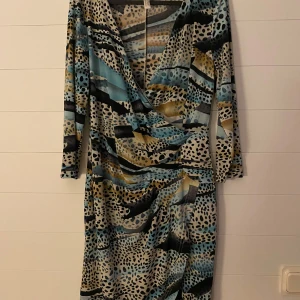 Mönstrad klänning från Body Flirt - Säljer en superfin mönstrad klänning från Body Flirt. Den har ett coolt leopardmönster i blå, beige och svarta toner. Klänningen är omlott med trekvartsärmar och en v-ringad hals. Perfekt för en festlig kväll eller en dag på stan!