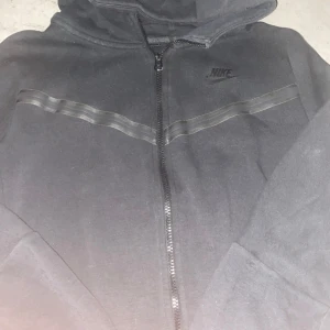 Nike teech fleece - Nike teech fleece med bra skick. En liten skada vid vänster hörn på fleecen med väldigt litet och knappt märkbart. Köpt 2022 för 1100kr men knappt använd då den blev förliten ganska snabbt:)