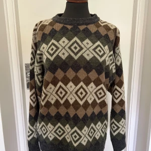 Mönstrad stickad tröja i jordnära färger - Säljer denna stickade tröja med mönster i brunt, beige och grått. Den är väldigt varm vilket gör den perfekt för höst och vinter! Tröjan har långa ärmar och en normal passform, vilket gör den både bekväm och stilren. Den är i nyskick 