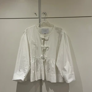 Vit blus med rosetter, LA RŌUGE - Vit blus med rosetter som knyter ihop den där fram.  Använd 2 gånger och tvättad 1 gång. Nyskick.  Strl M/L