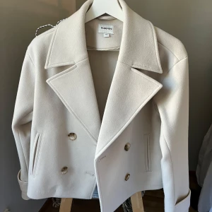 Beige kappa från Kappahl - Säljer en superfin beige kappa från Kappahl i storlek XS, passar även S. Den har dubbelknäppning och fickor på framsidan. Jackan har även ett band vid ärmslut med en knapp som en snygg detalj.  Perfekt för höst och vår! 🧥✨Inköpt för 899kr, nyskick!