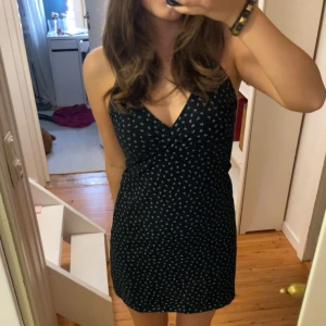 Svart blommig klänning från Brandy Melville!🖤 - Säljer en superfin svart klänning från Brandy Melville med små vita blommor. Den har en v-ringad design och smala axelband, perfekt för sommardagar eller en festkväll. Klänningen är i nyskick och har en tight passform som framhäver figuren.