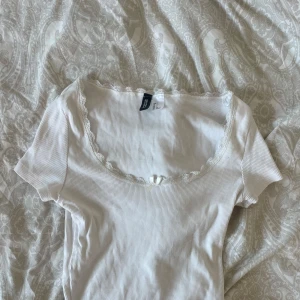 Spets tshirt  - Säljer en vit tshirt med spets detaljer med en vit rosset❣️ använt bara få gånger och är i bra skick💕