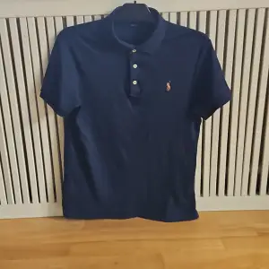 Säljer en snygg mörkblå piké från Ralph Lauren i storlek M, fint skick. Tröjan är slim fit och har korta ärmar med klassisk krage och knappar framtill. Perfekt för en stilren och avslappnad look!