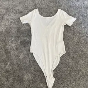 Säljer en stilren vit bodysuit i storlek M. Den är kortärmad och har en rund halsringning. Perfekt för att matcha med jeans eller kjol för en enkel och snygg look. Materialet känns mjukt och bekvämt mot huden.